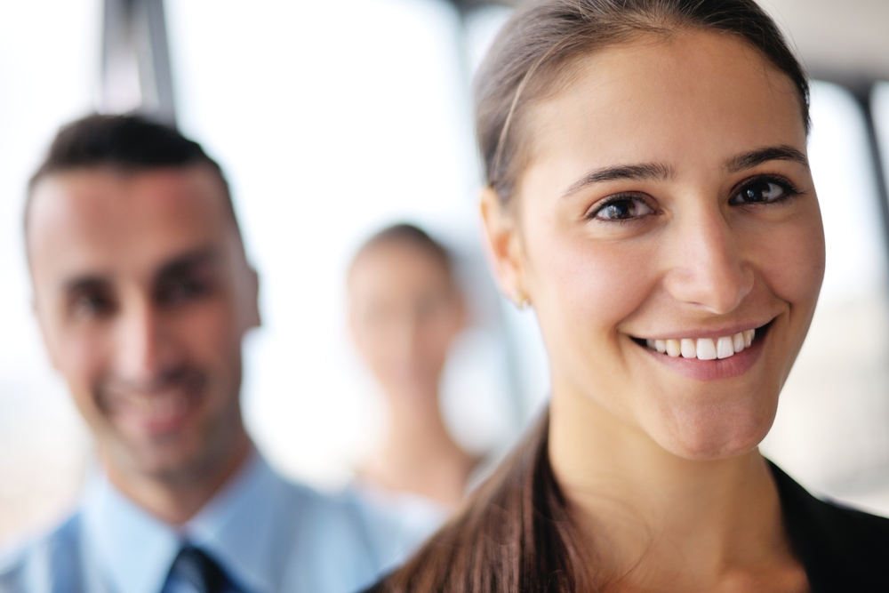 happy young business woman with her staff, people group in background at modern bright office indoors-1